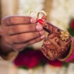 Home Close-up of hands with henna and jewelry during a traditional Indian wedding ceremony, exchanging rings.